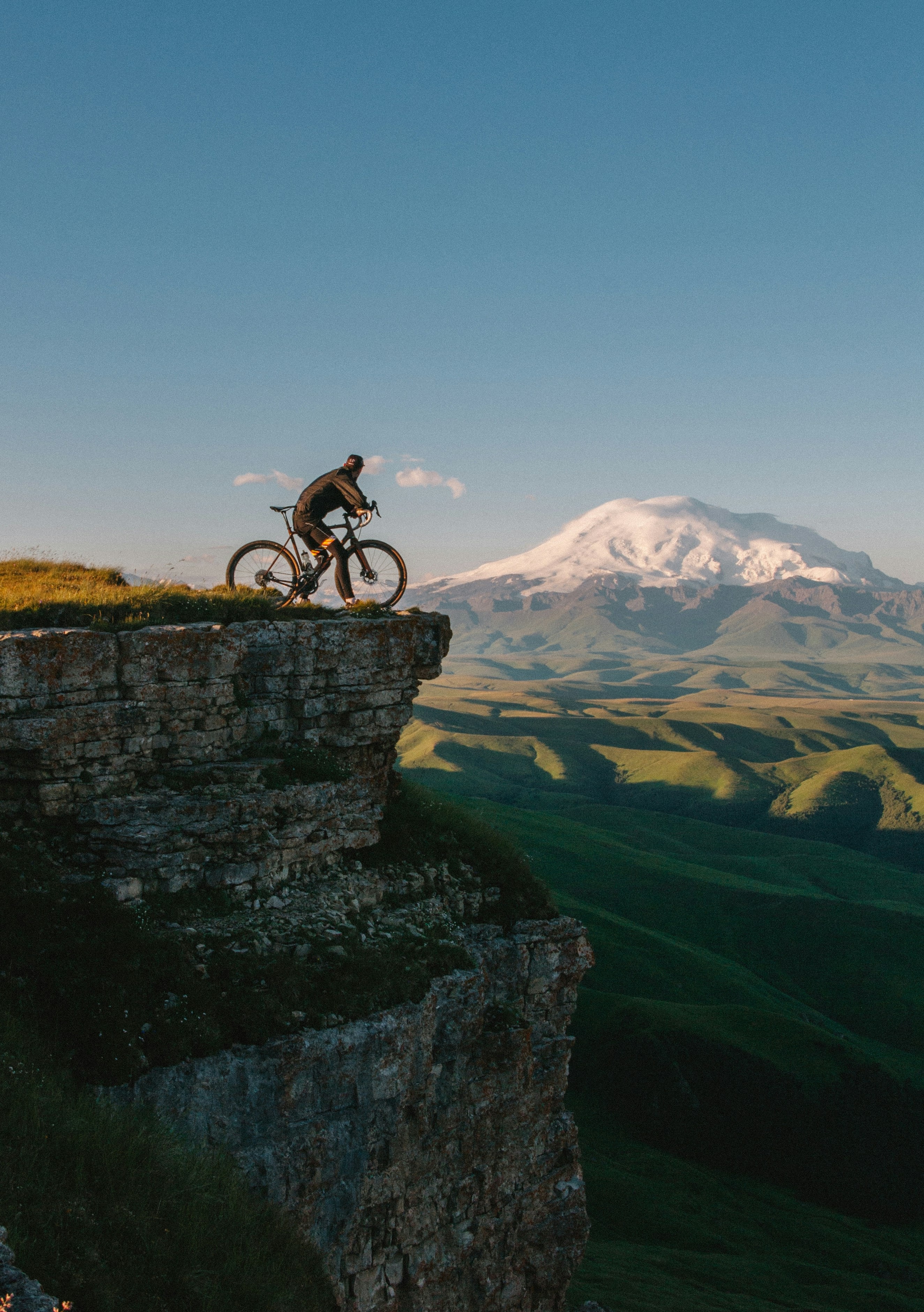 Cyclists riding a coastal road with sea views and a lighthouse on the horizon — one of seven scenic cycling routes in Europe featured in this guide.